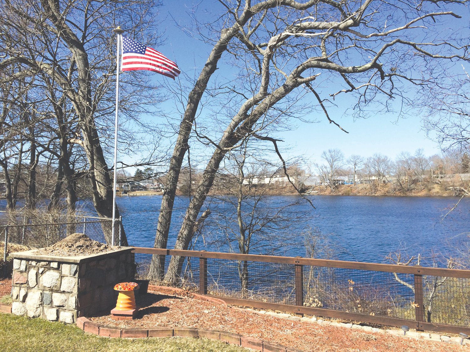 THE VIEW TODAY: Dave Bouchard provided this photo of Sand Pond, with flag flying, from his backyard looking north west at Pond Plaza. The self-storage unit being proposed for the site would be twice the height and extend to the right.